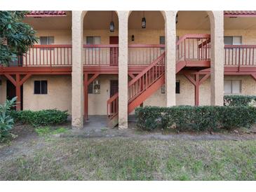 Exterior view of a two-story condo building with red accents, neutral paint, and multiple entrances at 2804 N Powers Dr # 27, Orlando, FL 32818