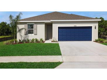 Charming single-story home with a well-manicured lawn, blue garage door, and neutral-colored exterior at 2950 Supermarine Rd, Tavares, FL 32778