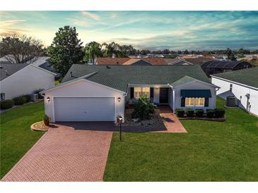 Well-maintained single-story home boasts beautiful landscaping, a two-car garage, and a charming brick driveway at 3218 Woodridge Dr, The Villages, FL 32162