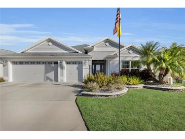 Charming single-story home featuring a well-manicured lawn, tropical landscaping, and a spacious two-car garage at 5819 White Ibis, The Villages, FL 32163