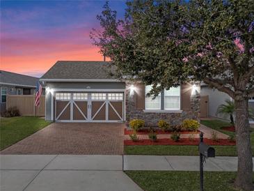 Charming home with a two-car garage, stone accents, complemented by brick pavers and lovely landscaping at 123 Bayou Bend Rd, Groveland, FL 34736