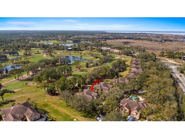 Expansive aerial view of a property nestled among lush golf course greens and shimmering lake waters at 202 Camino Real Blvd # 202, Howey In The Hills, FL 34737