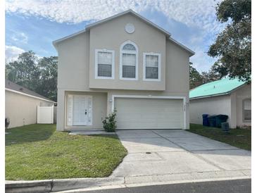 Two-story home featuring a two-car garage, a well-kept lawn, and a classic facade at 2320 Whispering Trails Pl, Winter Haven, FL 33884