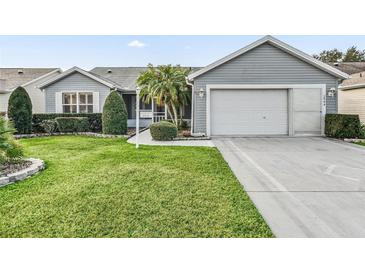 Charming single-story home with a well-manicured lawn, tasteful landscaping, and attached garage at 2444 Merida Cir, The Villages, FL 32162