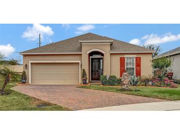 Charming single-story home featuring a paver driveway, two-car garage, and landscaped front yard at 245 Citrus Pointe Dr, Haines City, FL 33844