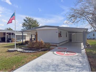 Charming single-story home featuring a covered driveway with a compass design, American flag, and well-maintained landscaping at 730 Royal Palm Ave, The Villages, FL 32159