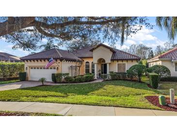 Charming single-story home featuring a tile roof, lush landscaping, and an inviting front yard with mature trees at 9930 Santa Barbara Ct, Howey In The Hills, FL 34737