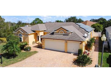 Charming home featuring a three-car garage, brick driveway, and manicured landscaping at 100 Grand Reserve Dr, Davenport, FL 33837