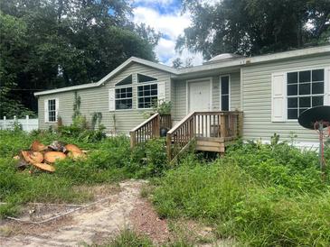 View of a single story home with a small porch surrounded by overgrown foliage at 100 Se 81St St, Ocala, FL 34480