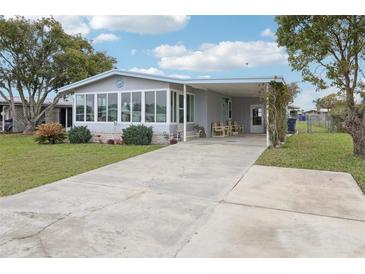 Charming home features an enclosed porch with lots of windows, carport, landscaping and a concrete drive at 1430 Mohawk Cir, Tavares, FL 32778