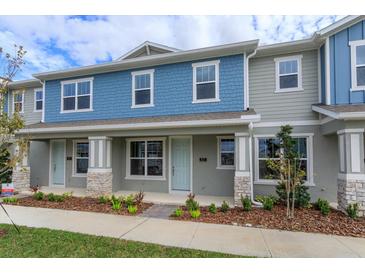 Charming townhome featuring a two-story facade with blue and gray accents, complemented by a well-manicured front yard at 16434 Hamlin Hills Rd, Winter Garden, FL 34787