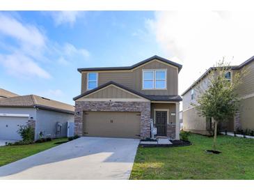 Two-story home with stone accents, a well-maintained lawn, and a two-car garage at 2024 Hemingway Cir, Groveland, FL 34736