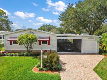 Charming home featuring awning-covered windows, a carport and a brick driveway, all beautifully landscaped at 25605 Belle Alliance, Leesburg, FL 34748