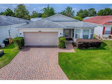Charming single-story home featuring a two-car garage, brick driveway, and manicured lawn at 32708 Westwood Loop, Leesburg, FL 34748