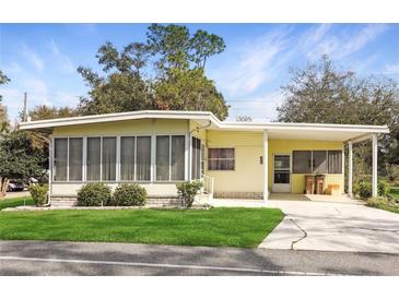 Charming yellow single-story home with screened porch, carport, and well-manicured lawn at 354 Hawthorne Blvd, Leesburg, FL 34748