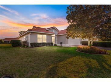 Charming single Gathering home featuring lush landscaping, warm colors, and a red tile roof at sunset at 5049 Harbour Dr # 1, Oxford, FL 34484