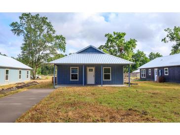 Charming blue single-story home with a metal roof and covered porch, offering classic curb appeal at 654 Nw 9Th Ave, Webster, FL 33597