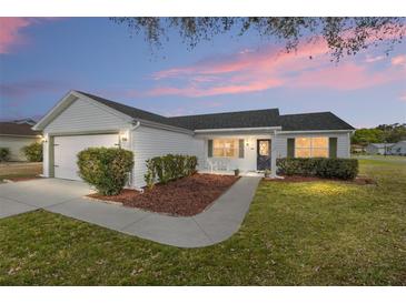 Charming single story home with white siding, tidy landscaping, and an attached garage at dusk at 901 Chula Ct, The Villages, FL 32159