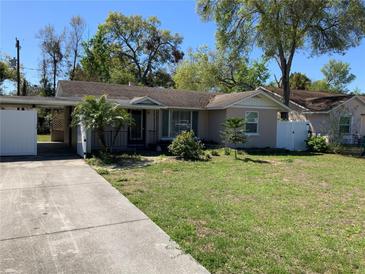 Charming one-story house features a carport and a well-manicured front lawn adorned with lush trees at 100 W Idlewild Ave, Eustis, FL 32726