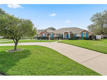 Well-maintained single-story home with bright blue shutters, mature landscaping, and a long driveway leading to the entrance at 10230 Barrington Ct, Leesburg, FL 34788