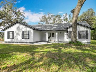 Charming single-story home featuring a manicured lawn and inviting entryway at 12220 County Road 209, Oxford, FL 34484