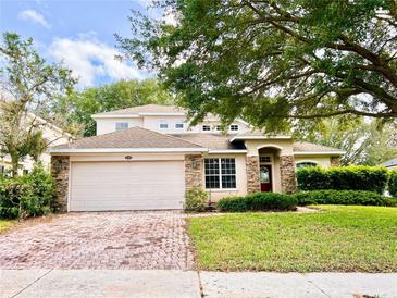 Charming two-story home featuring a brick driveway, two-car garage, and lush landscaping at 1263 Legendary Blvd, Clermont, FL 34711