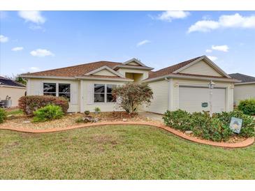 Charming single-story home featuring a well-manicured lawn and a two-car attached garage at 1273 Oak Forest Dr, The Villages, FL 32162