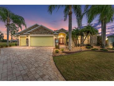 Beautiful front exterior with stone accents, paver driveway and tropical landscaping, showcasing its curb appeal at 1312 Patrick Pl, The Villages, FL 32162