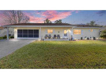 Charming single-story home features a screened garage, inviting front porch with seating, and well-manicured lawn at 17813 Se 95Th Ct, Summerfield, FL 34491