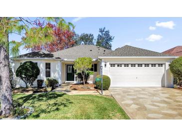 Charming one-story home with a well-manicured lawn, stone driveway, and attached two-car garage at 17979 Se 89Th Rothway Ct, The Villages, FL 32162