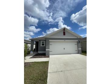 Charming gray single-story home featuring a two-car garage and well-maintained lawn at 1799 Post Oak Dr, Davenport, FL 33837