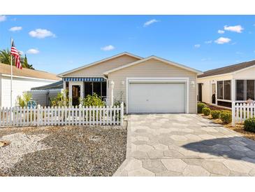 Charming single-story home features a well-manicured lawn, white picket fence, and attached garage at 2495 Birch Ave, The Villages, FL 32162