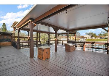 Large wooden deck features a covered seating area and views of the surrounding water and neighborhood at 26608 E Cove Dr, Tavares, FL 32778