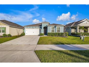 Charming single-story home featuring a manicured front yard and a two-car garage at 28026 Cypress Springs Loop, Okahumpka, FL 34762