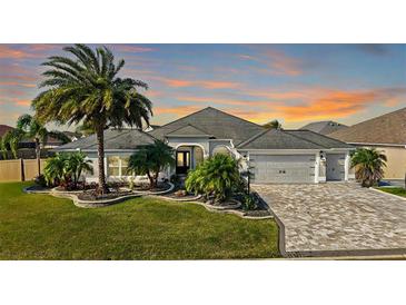 Beautiful single-story home featuring lush landscaping, a paved driveway, and a two-car garage at 3261 Wise Way, The Villages, FL 32163