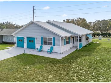 Charming single-story home featuring a metal roof, two-car garage, and well-manicured lawn at 701 Brigadoon Cir, Leesburg, FL 34788