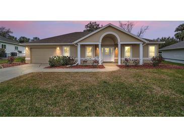 Charming single-story home featuring a well-manicured lawn and inviting entrance with white columns at 11053 Se 174Th Loop, Summerfield, FL 34491