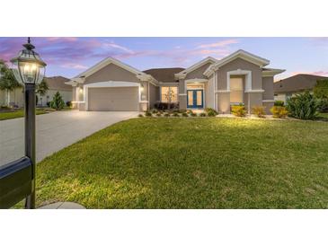 Charming home featuring a well-manicured lawn, a two-car garage, and a welcoming facade at 13146 Se 91St Court Rd, Summerfield, FL 34491