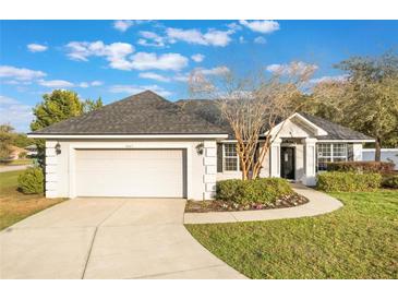 Charming single-story home with a well-manicured lawn and a two-car garage, enhanced by beautiful landscaping and a cozy entryway at 1603 Brookstone Ln, Fruitland Park, FL 34731