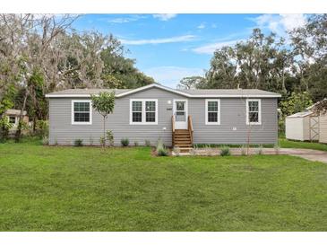 Charming single-story home with gray siding, well-maintained landscaping and inviting front porch at 17442 Eve Dr, Montverde, FL 34756