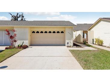 Home exterior featuring attached front entry garage with long driveway and manicured landscaping at 2229 Cypress Ct # C-4, Tavares, FL 32778