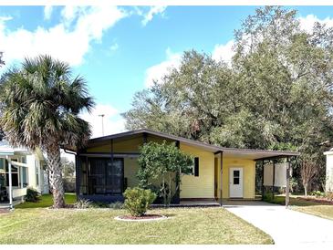 Charming single-story home with a covered carport, screened porch, and lush green lawn at 224 Westwood Dr, Leesburg, FL 34748