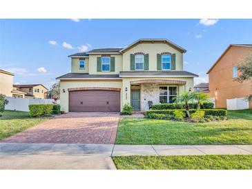 Charming two-story home featuring a brick-paved driveway, manicured lawn, and an inviting front porch at 2727 Retriever Dr, Clermont, FL 34711