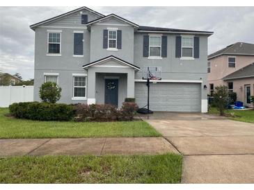 Charming two story home featuring blue exterior, well manicured lawn, and two car garage at 303 Red Kite Dr, Groveland, FL 34736