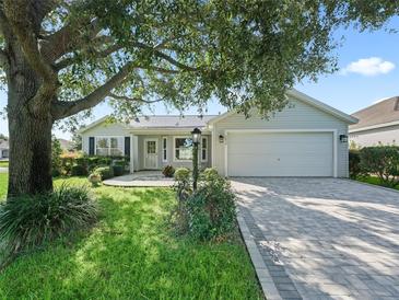 Charming single-story home with a well-manicured lawn, brick driveway, and attached two-car garage at 1414 Georgetown Ave, The Villages, FL 32162