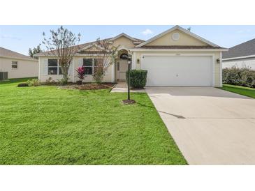 Charming single-story home with lush lawn, well-manicured landscaping, and a two-car garage at 1904 Augustine Dr, The Villages, FL 32159