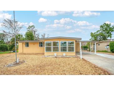 Charming home with large windows and covered parking, set against a bright blue sky at 2714 Vindale Rd, Tavares, FL 32778