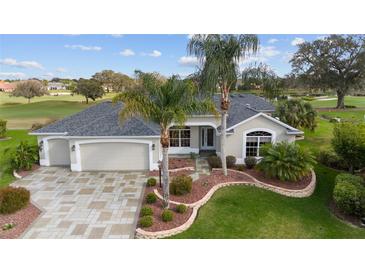 Charming home with a well-manicured lawn, beautiful landscaping, and a paved driveway leading to a two-car garage at 3234 Berkeley Ln, The Villages, FL 32162