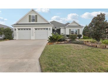 Charming one-story home featuring a well-manicured lawn, landscaping, and a two-car garage at 960 Pickering Path, The Villages, FL 32163
