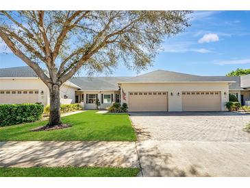 Charming home featuring a three-car garage, manicured lawn, and mature tree in a serene setting at 1037 Green Gate Blvd, Groveland, FL 34736